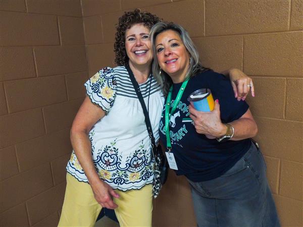 two teachers hugging in hallway